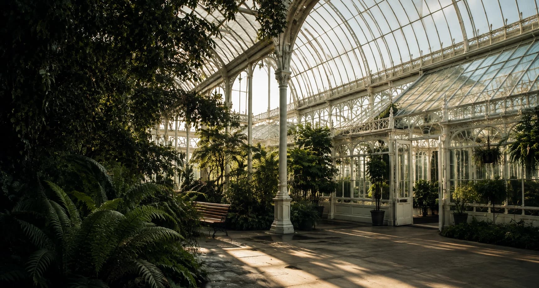 The domed interior of Kibble Palace, tree ferns and iron framework lit by evening light.